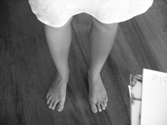 black and white photograph of a woman's feet on a wooden floor